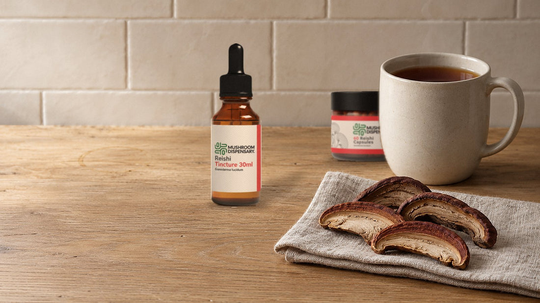 Mushroom Dispensary Reishi Tincture 30ml and Reishi Capsules on an oak worktop with a mug of tea and dried reishi slices on linen